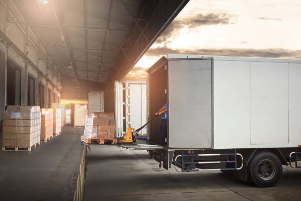 Package Boxes on Pallets Loading into Cargo Container. Trucks Parked Loading at Dock Warehouse. Delivery Service. Shipping Warehouse Logistics. Road Freight Truck Transportation.