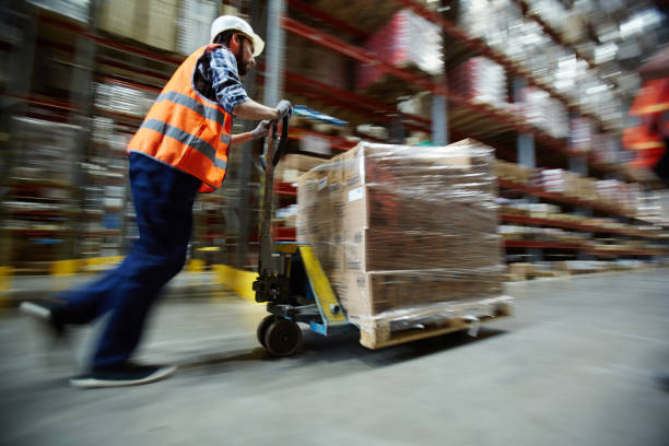 Warehouse worker pushing forklift at work